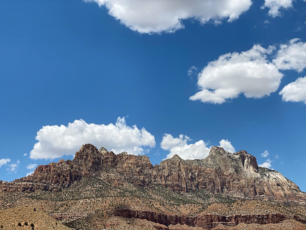 brown rocky mountain under blue sky and white clouds during daytime