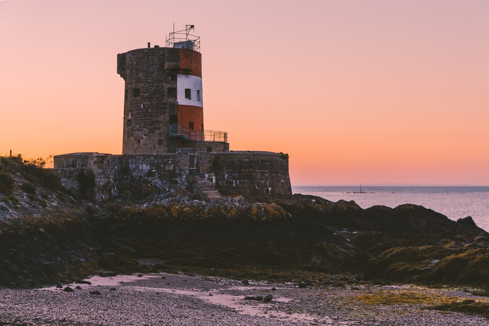 white and brown concrete lighthouse near body of water during daytime