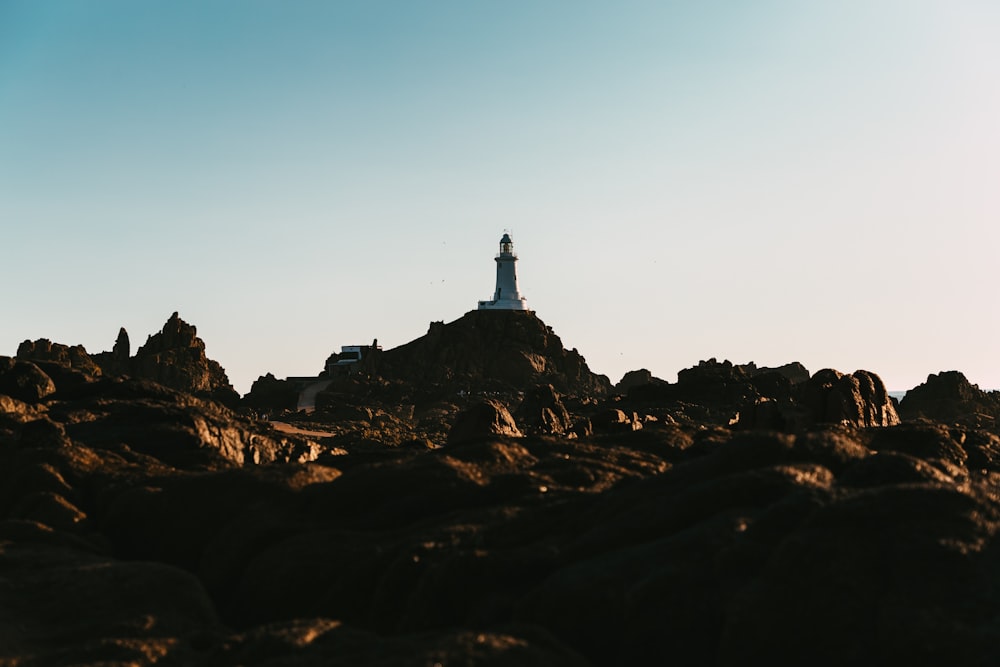 white and black tower on brown rock formation under blue sky during daytime