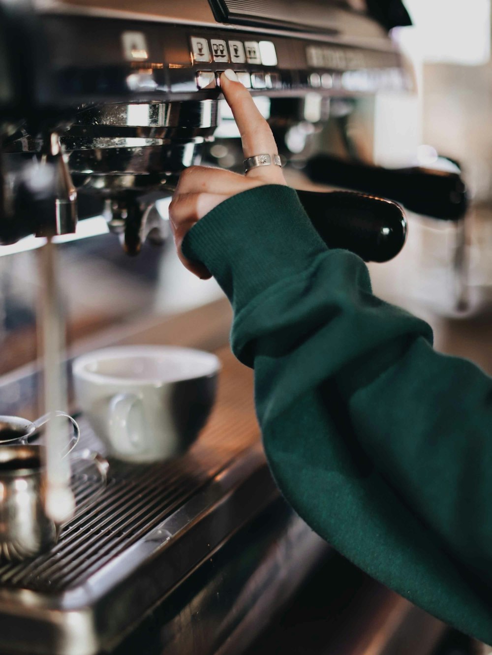 person in green long sleeve shirt holding silver and black espresso machine