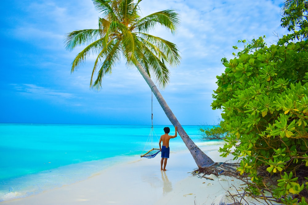 woman in black dress walking on beach during daytime