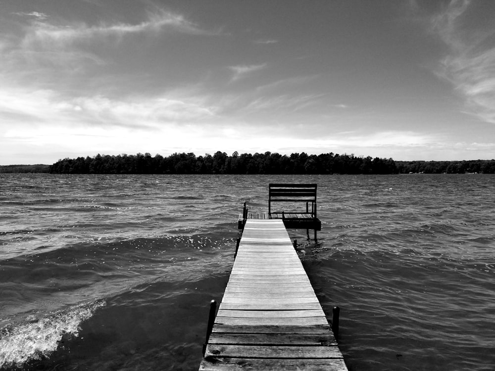 grayscale photo of wooden dock on body of water