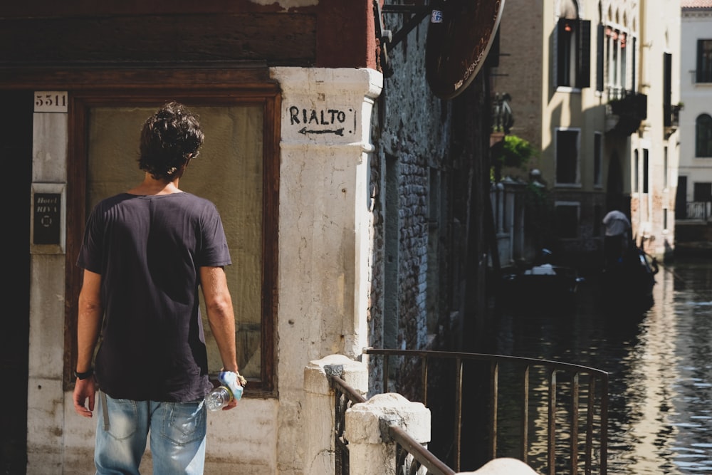 Homme en t-shirt à col rond bleu et jean en denim bleu debout à côté d’une clôture en métal blanc