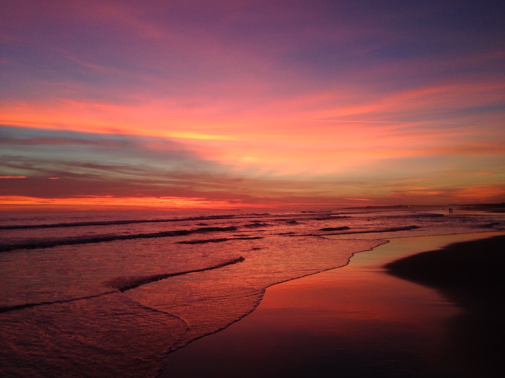 ocean waves crashing on shore during sunset