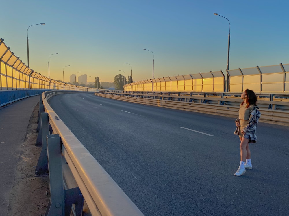 woman in white shirt and white shorts walking on gray concrete road during daytime