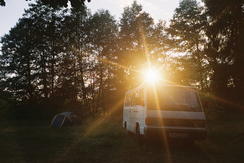 white van parked beside green trees during daytime