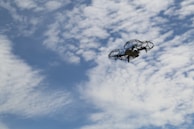 Test flight of an unmanned aerial vehicle prototype soaring against a blue sky dotted with soft clouds.