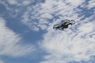 Test flight of an unmanned aerial vehicle prototype soaring against a blue sky dotted with soft clouds.