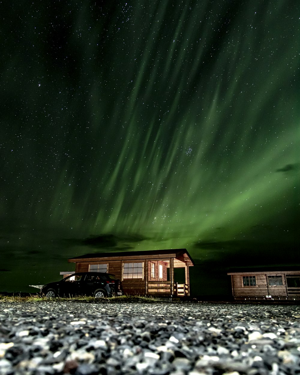 a cabin under the northern lights with a truck parked in front of it