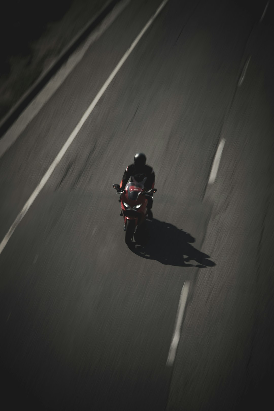 man in black and red jacket riding on blue and black motorcycle