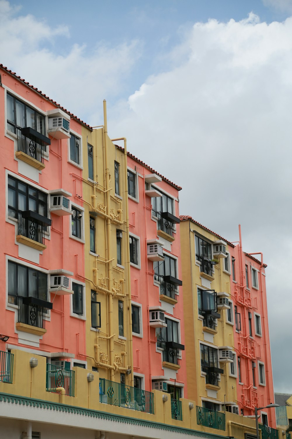 Edificio de hormigón amarillo y rojo bajo nubes blancas durante el día