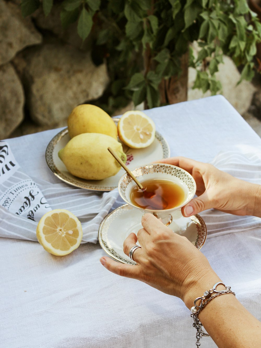 person holding white ceramic teacup with saucer with sliced lemon