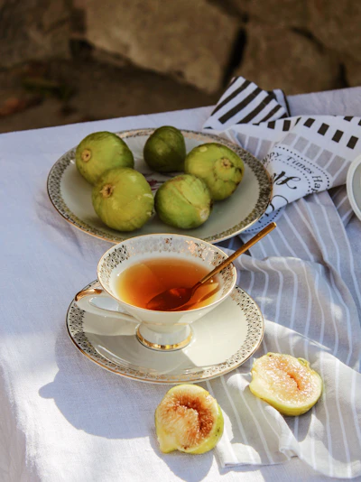 A steaming cup of fig leaf tea on a cozy wooden table with dried fig leaves scattered around.