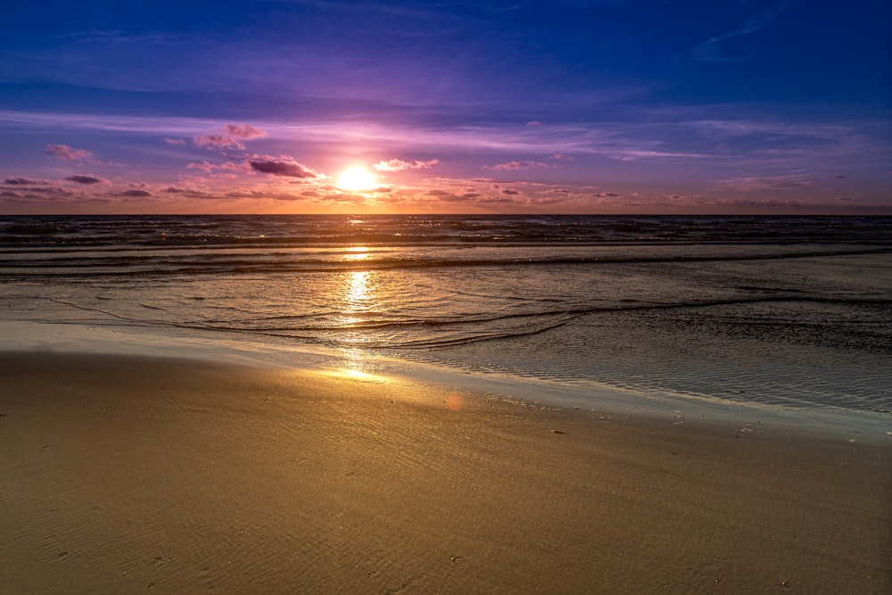 sea waves crashing on shore during sunset