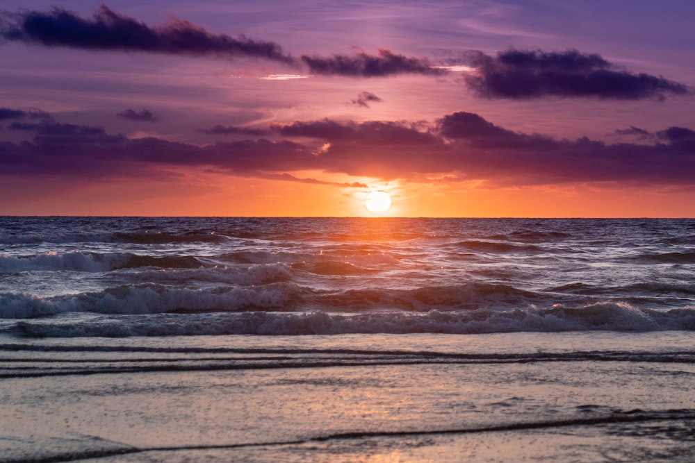 Meereswellen stürzen während des Sonnenuntergangs an Land