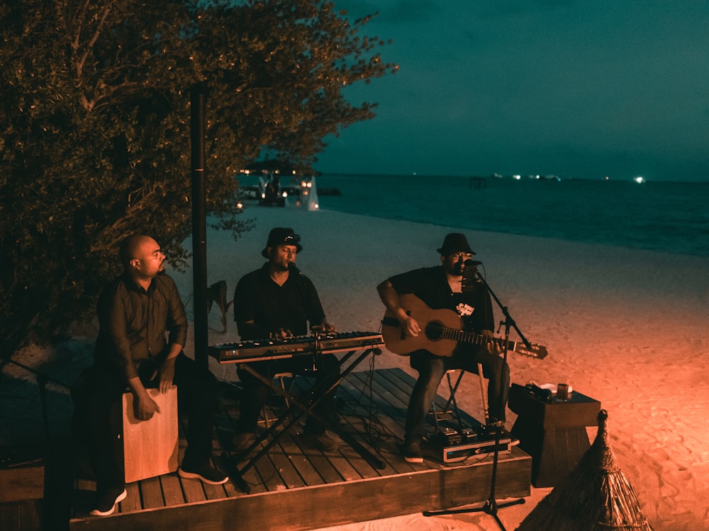 3 men playing musical instruments on dock during daytime