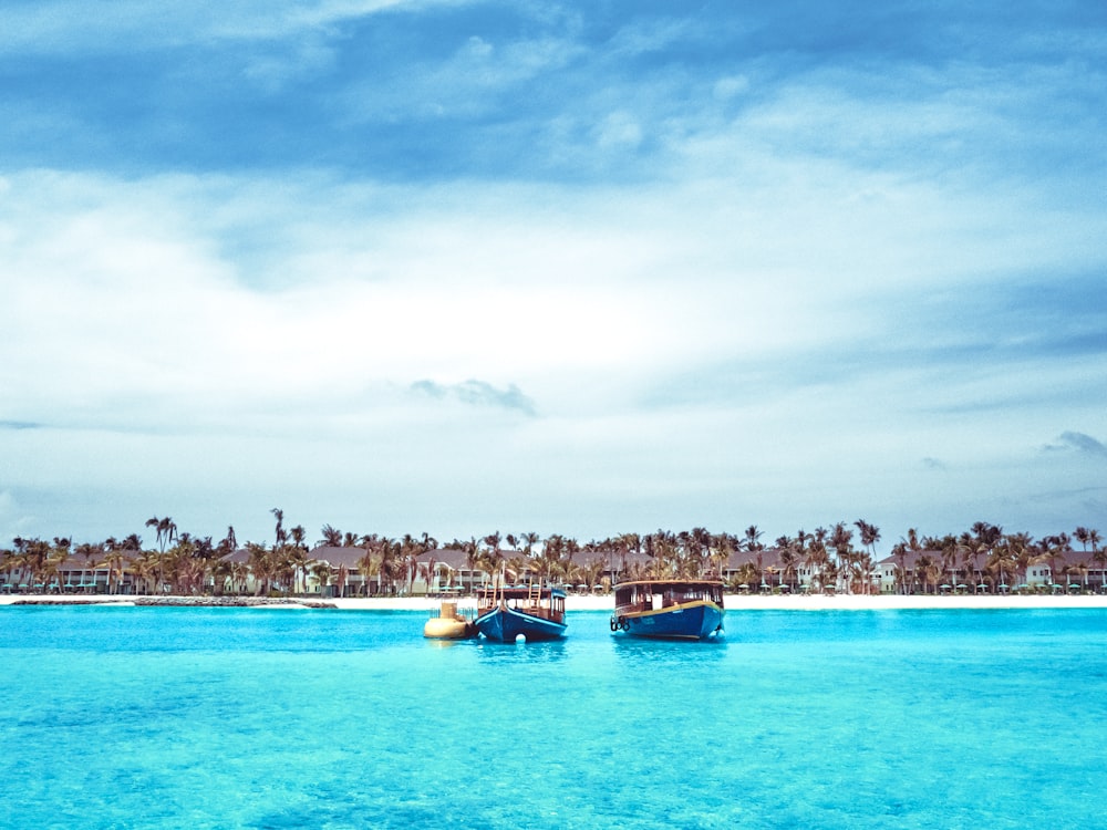 blue and white boats on blue sea under white clouds and blue sky during daytime