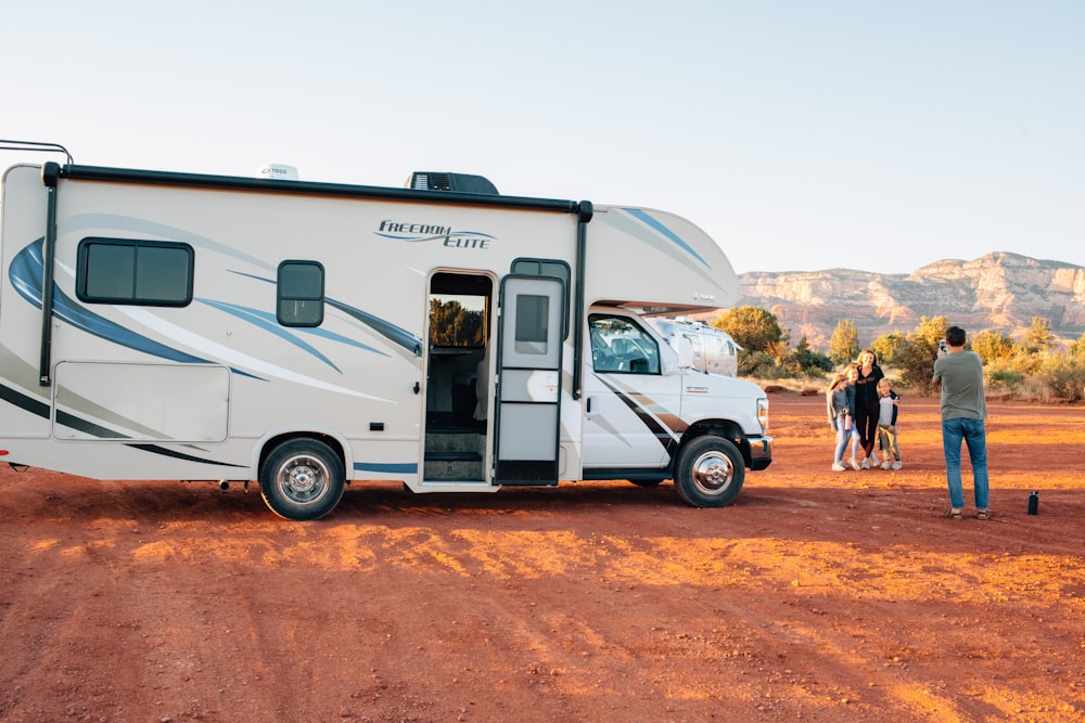 white and brown rv trailer on brown sand during daytime