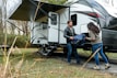 A cheerful family setting up a pop-up camper at a sunny campsite