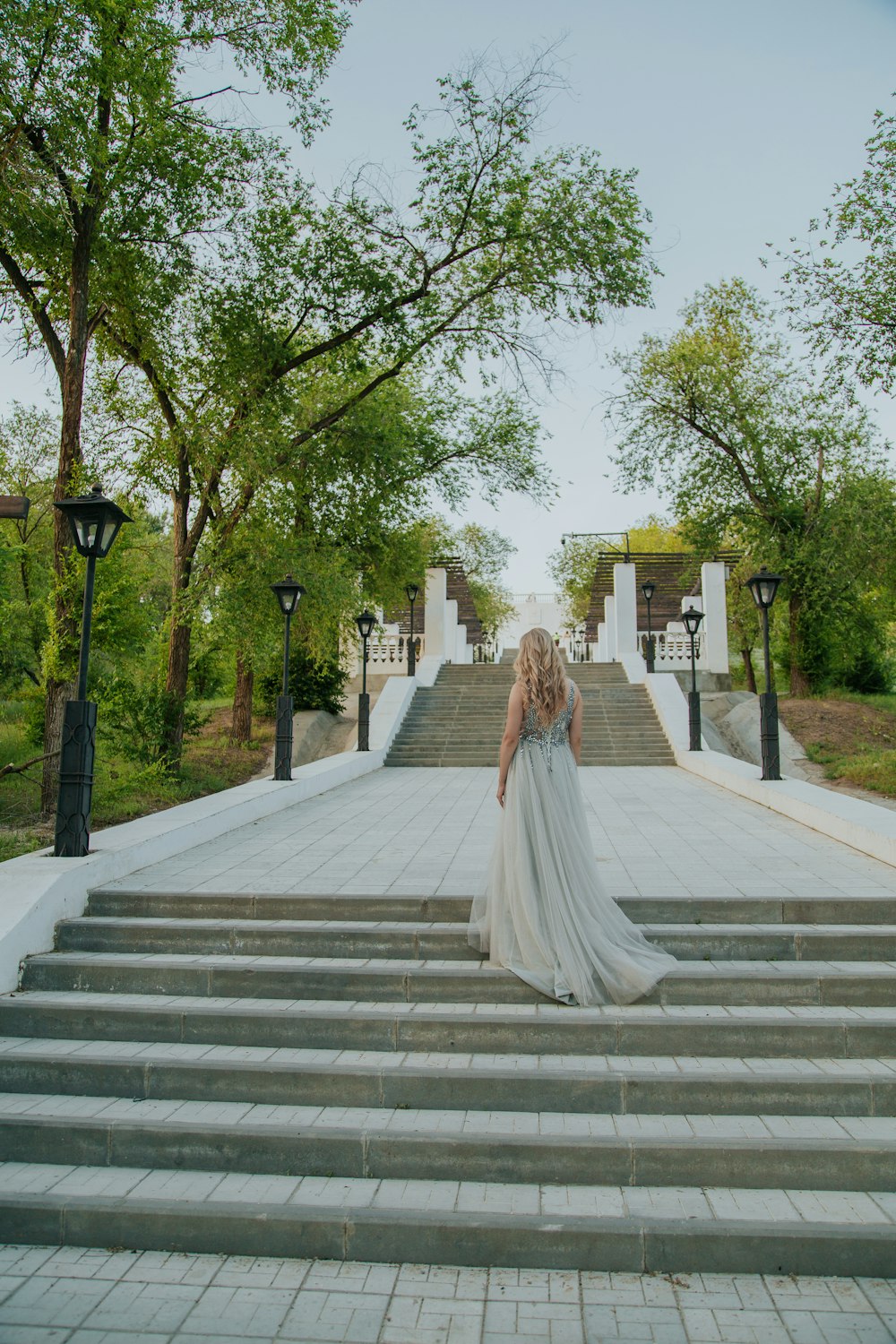 Mujer en vestido blanco caminando en escaleras de hormigón gris