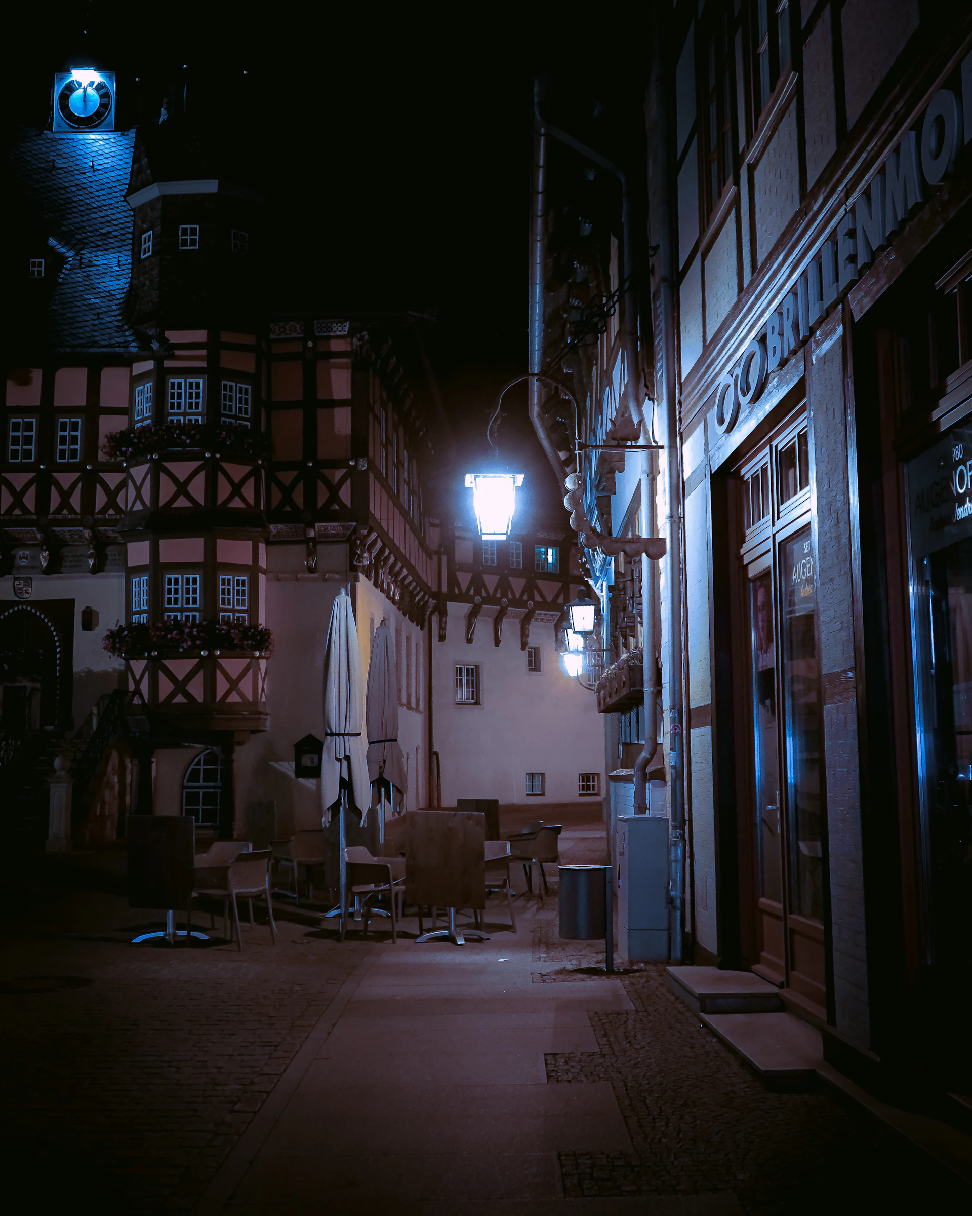 A misty twilight scene of Coal Gulch's deserted main street, with flickering lanterns casting eerie shadows on weathered wooden buildings.