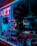 A store display window features various accessories, including purses and handbags, under vibrant blue and pink neon lighting. The interior of the store is dimly lit, highlighting the colorful and artistic presentation of the products.