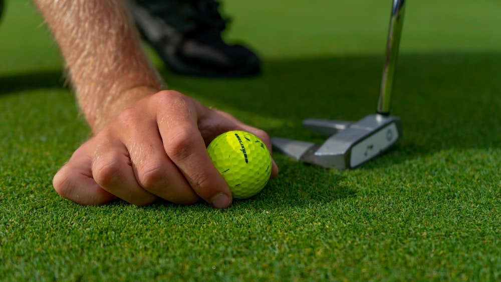 personne tenant une balle de golf jaune