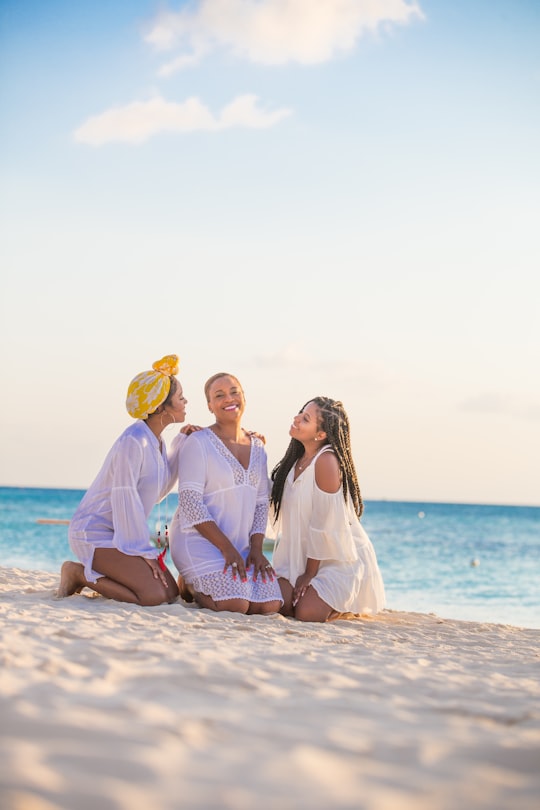 woman in white dress sitting on beach during daytime in Belize City Belize