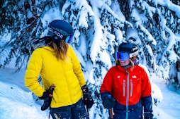 man in yellow jacket and blue knit cap standing on snow covered ground during daytime