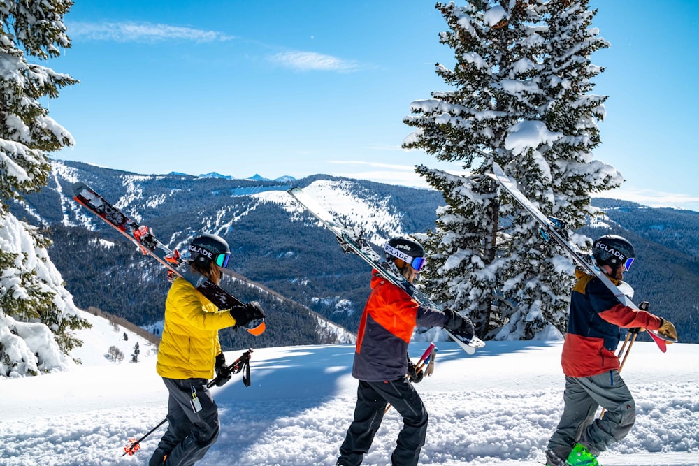 3 mensen die met ski's in hun handen de berg op lopen 