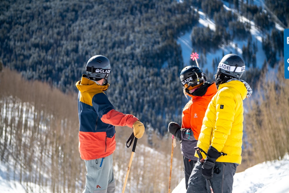 2 men in red and yellow jacket and helmet riding ski blades on snow covered mountain