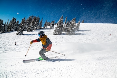 person in red jacket and blue pants riding on ski blades on snow covered ground during