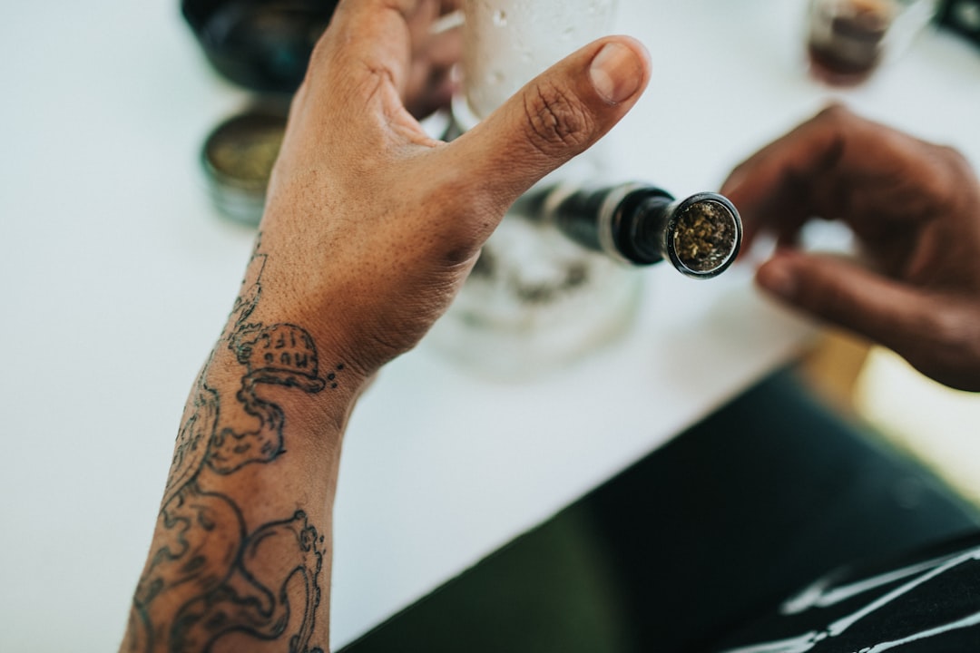 person with tattoo holding clear drinking glass