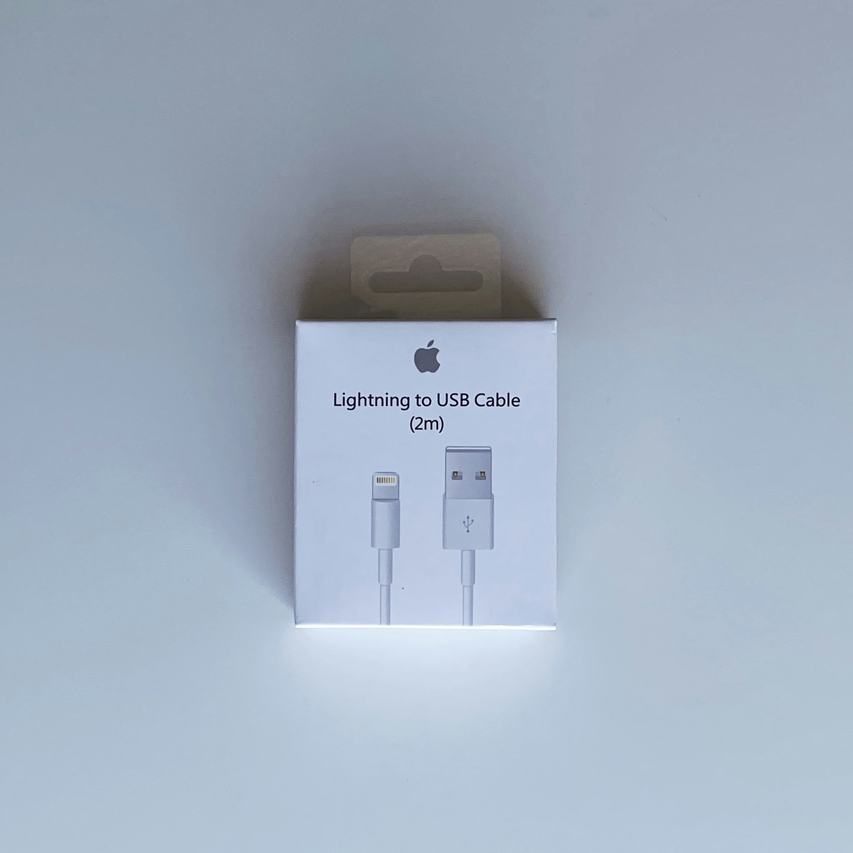 Apple Lightning cable coiled on white surface, 2 meter length, official Apple accessory