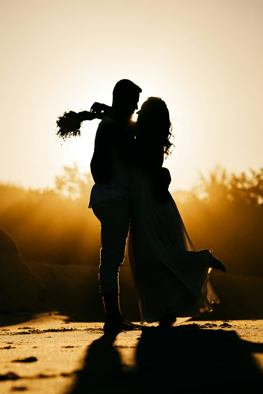 silhouette of man and woman kissing during sunset