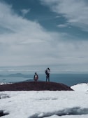 Hikers standing atop a mountain ridge, gazing at a vast valley below.