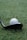 A close-up of a golf ball positioned on grass near the head of a golf club, with the text 'VERO X1' visible on the ball.