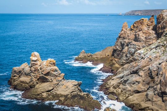 brown rock formation on sea during daytime in Pointe du Raz France