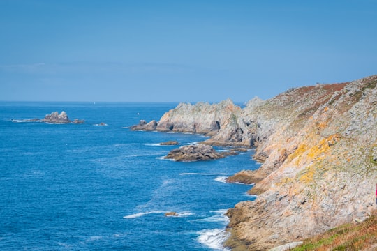 brown and green mountain beside blue sea under blue sky during daytime in Pointe du Raz France