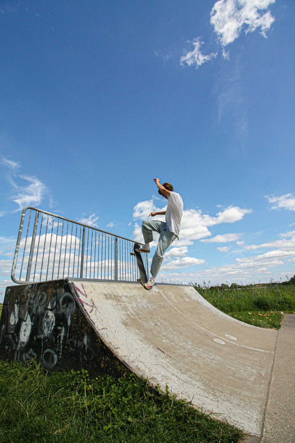 man in white long sleeve shirt and white pants jumping on brown concrete bridge during daytime