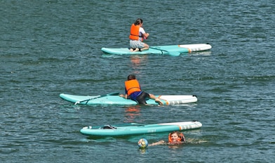 paddle boarding self rescues. People in bouyancy aids climb onto their board. 