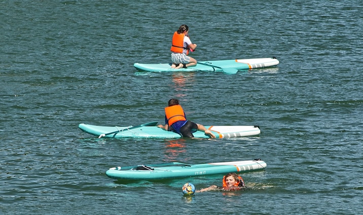 2 women in blue and red bikini on green and white inflatable float on water during