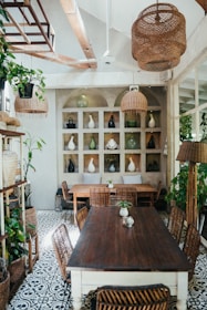 A rustic wooden dining table set with ceramic dishes and gentle, natural light streaming through palm fronds.