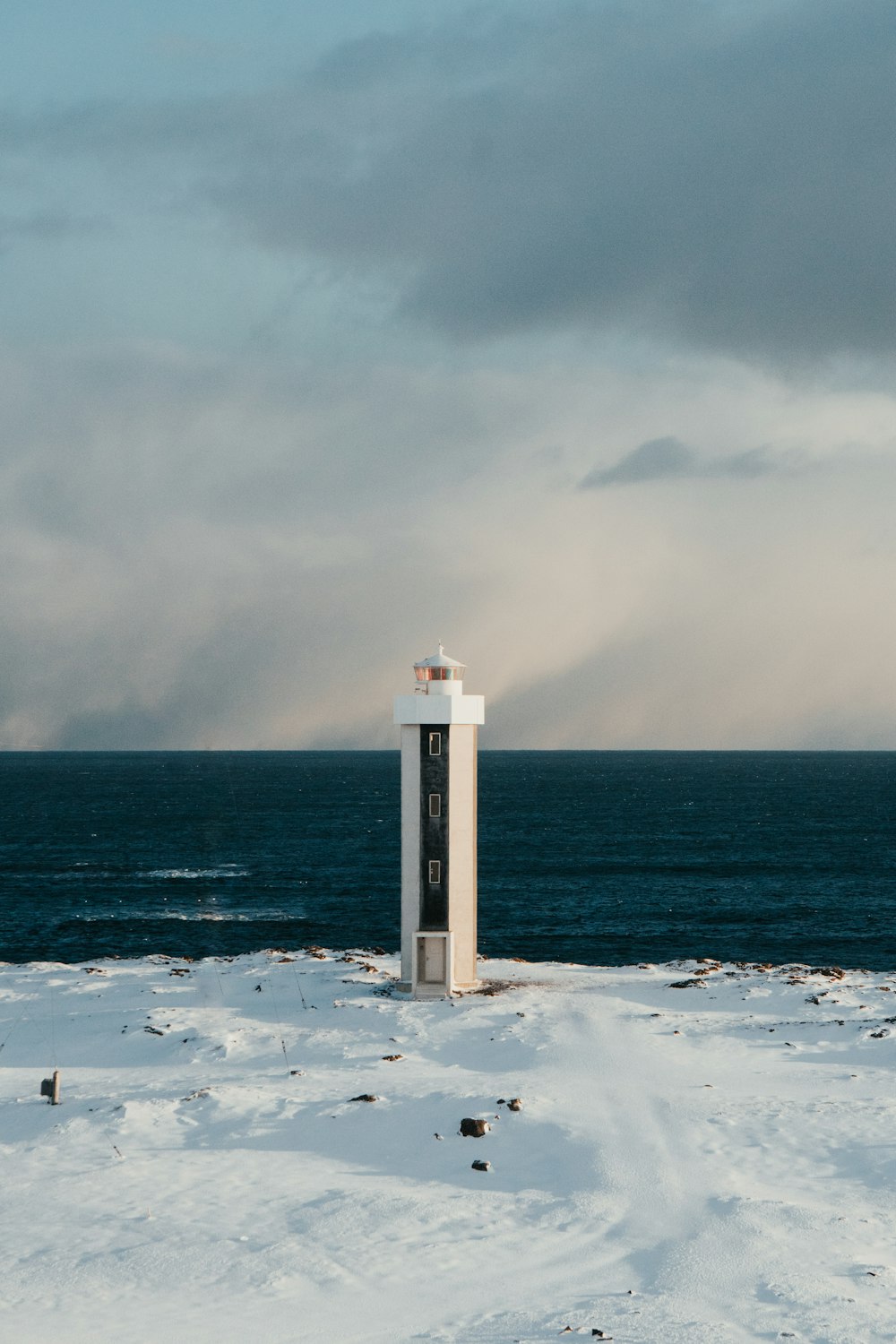 white and brown lighthouse on white snow covered ground during daytime