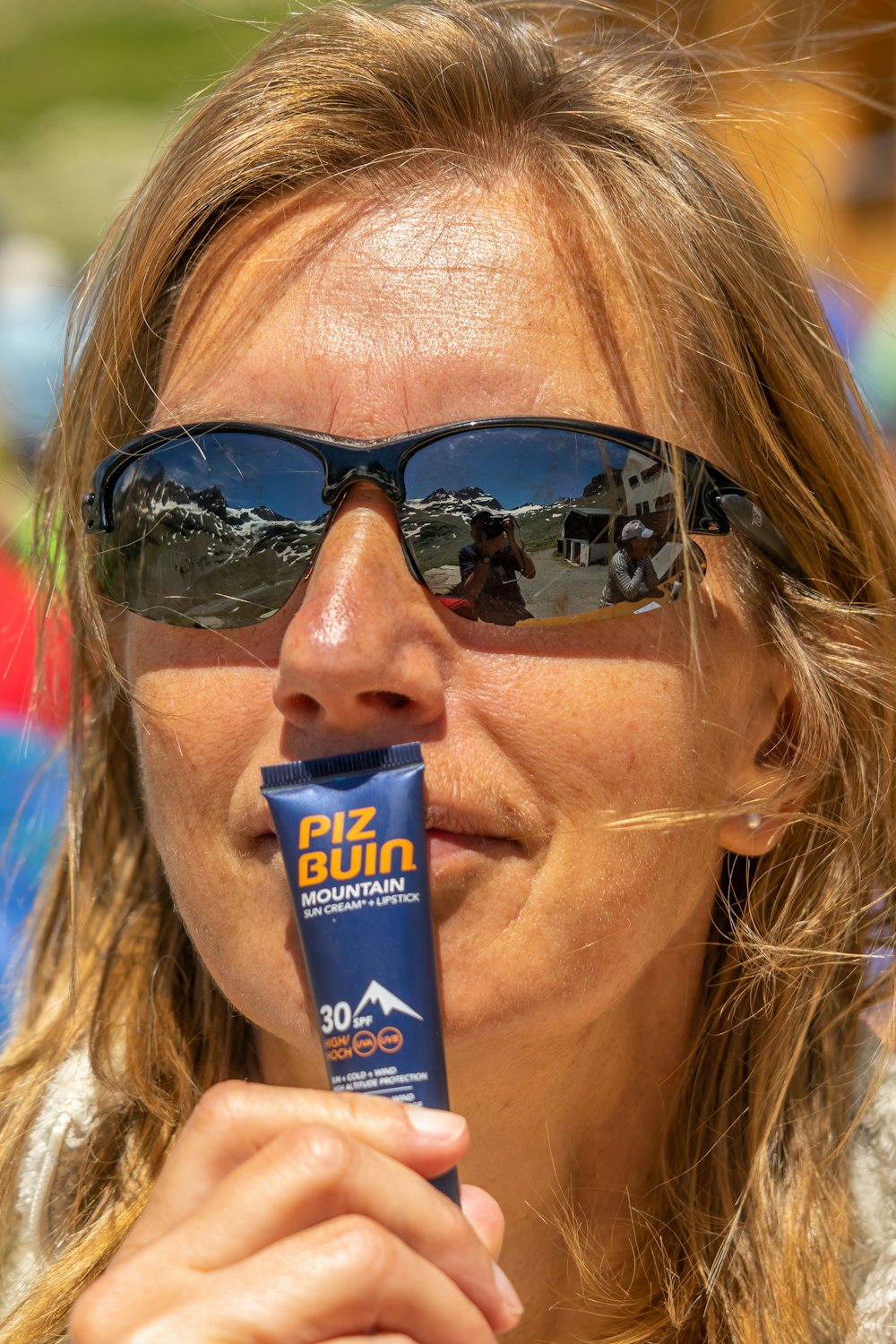 Femme en lunettes de soleil noires tenant une bouteille tube bleue