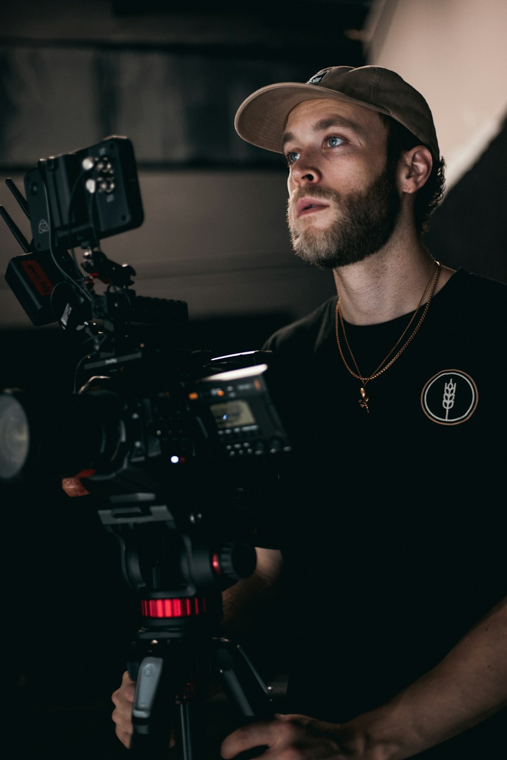 man in black crew neck shirt wearing black cap holding black video camera