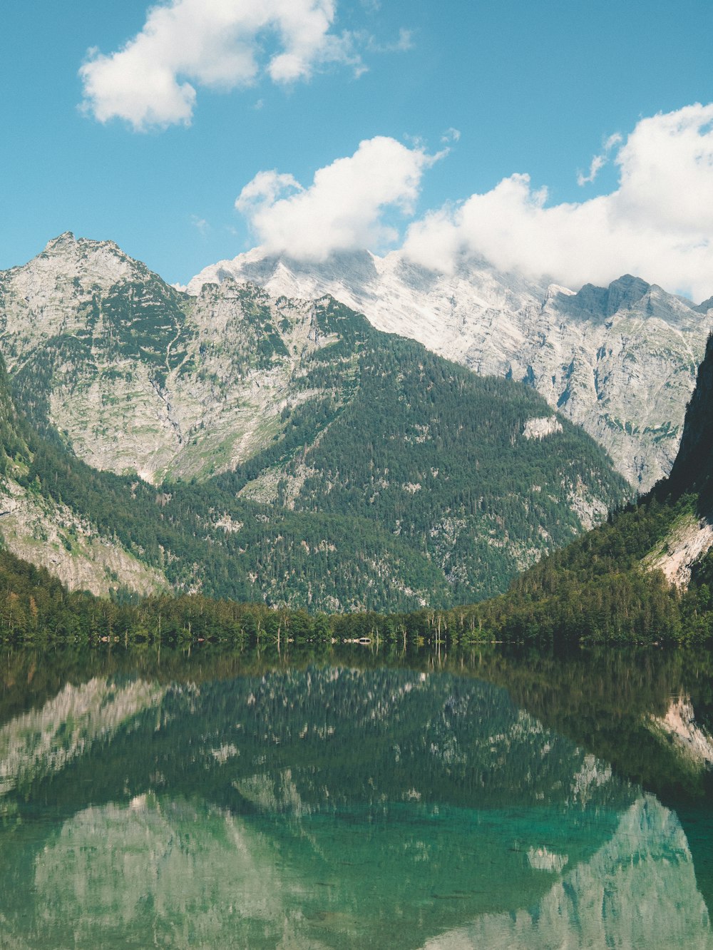 green and white mountain near lake under blue sky during daytime