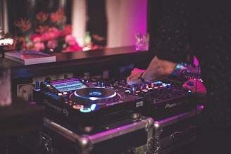 Close-up of DJ equipment with hands mixing tracks in a tropical setting.