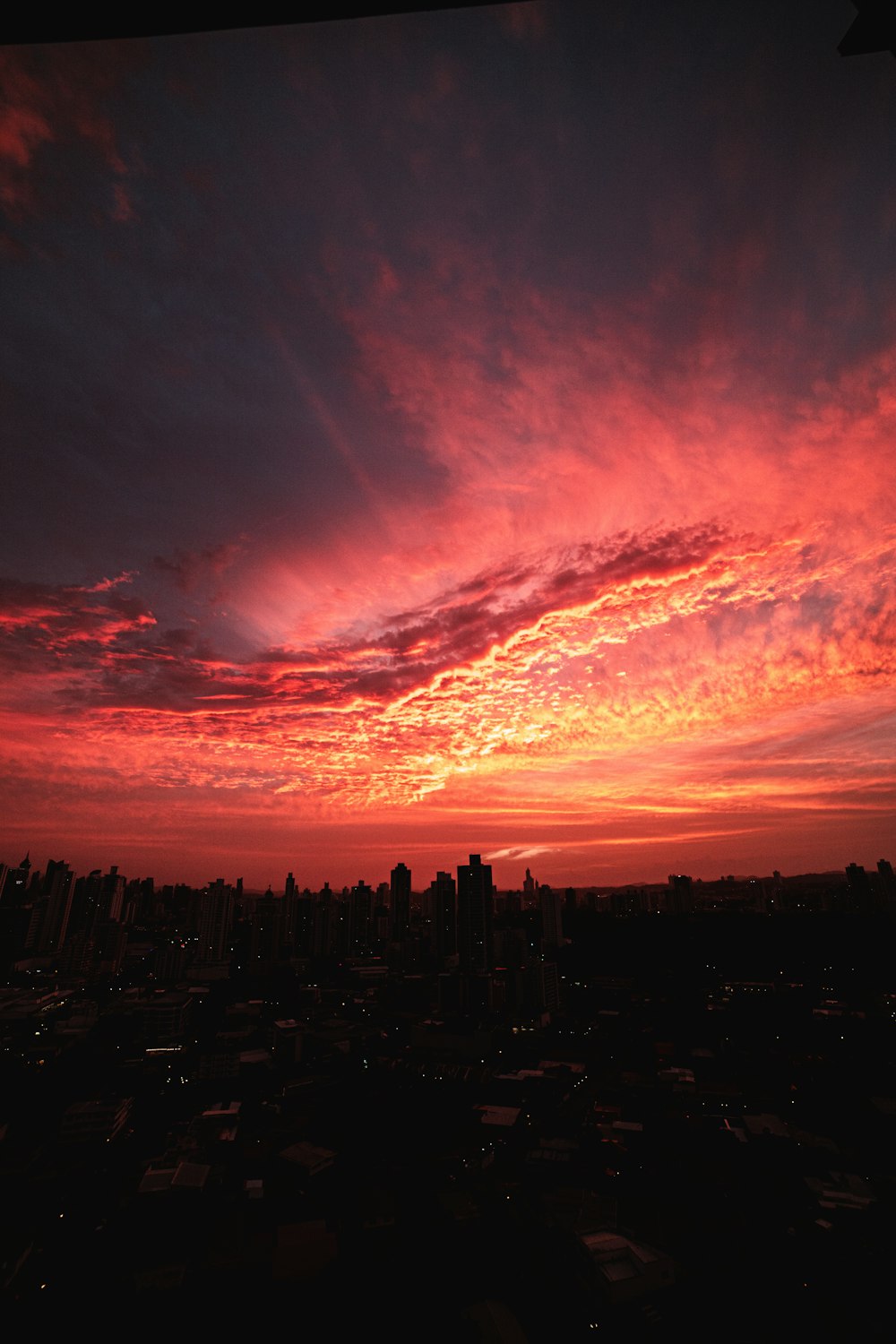 silhouette of city buildings under orange and blue cloudy sky during sunset