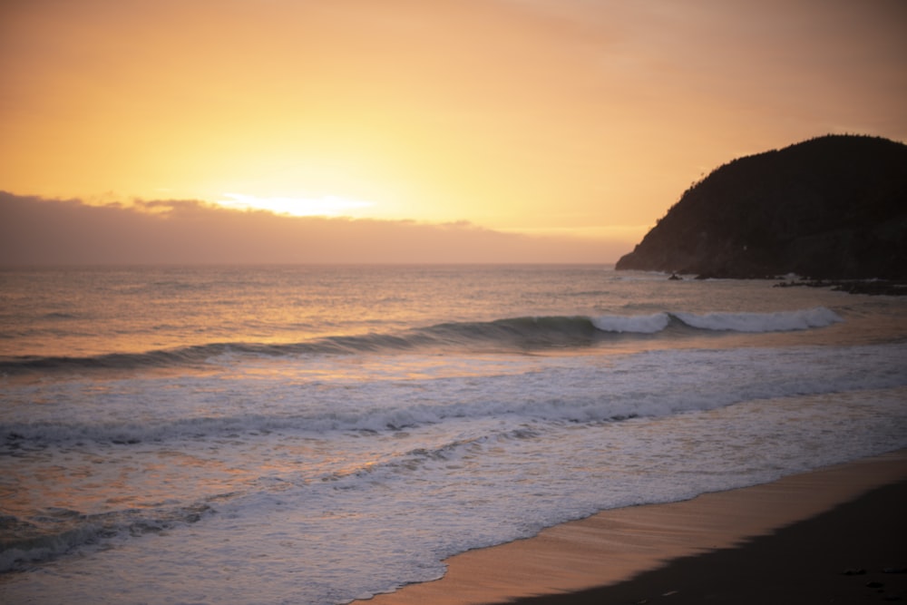 ocean waves crashing on shore during sunset